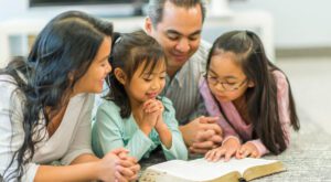 Parents and two girls reading bible together